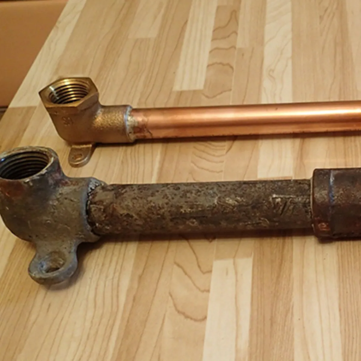 Old corroded lead service line next to a modern copper replacement pipe — Michigan lead pipe replacement mandate.