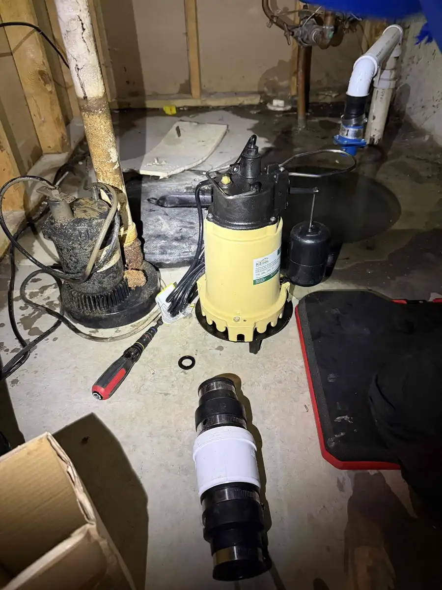 Old submersible sump pump on the basement floor next to the new replacement pump ready to install