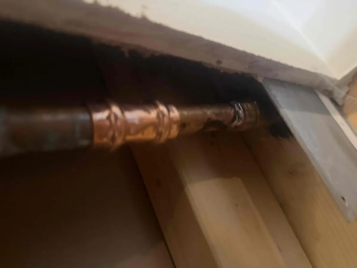New copper pipe section joined with press fittings inside an opened ceiling after a freeze burst