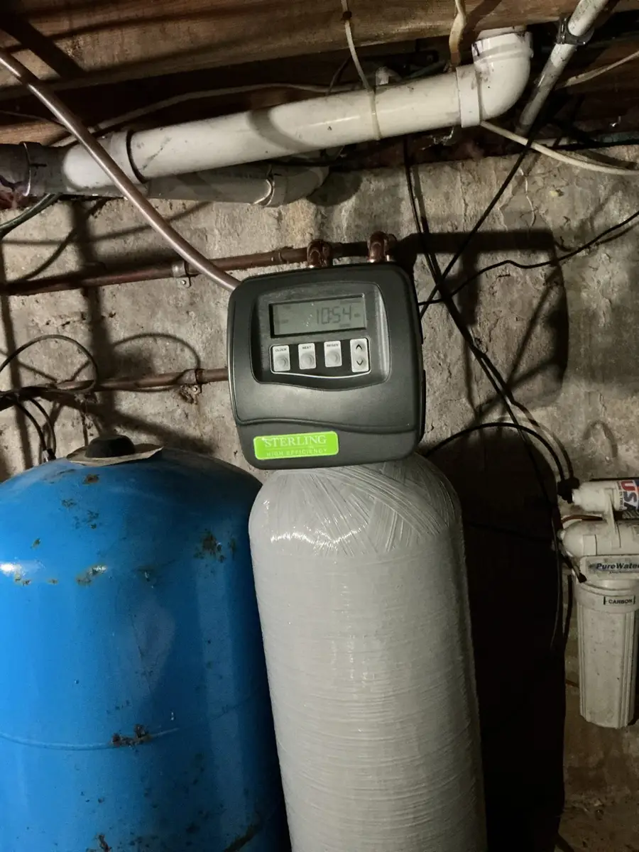 Softener control head mounted on a resin tank next to a well pressure tank