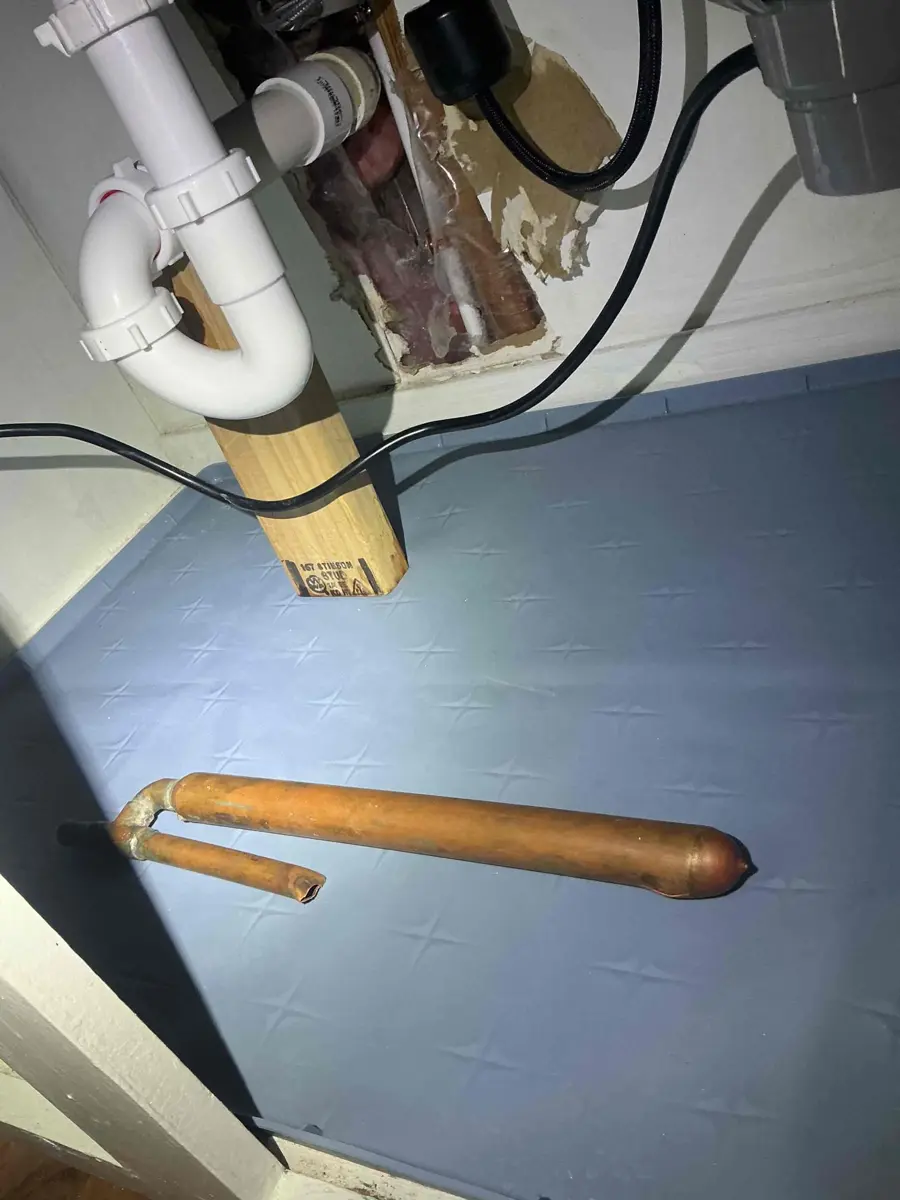 Section of copper water pipe with a split along its length, removed from a wall after freezing
