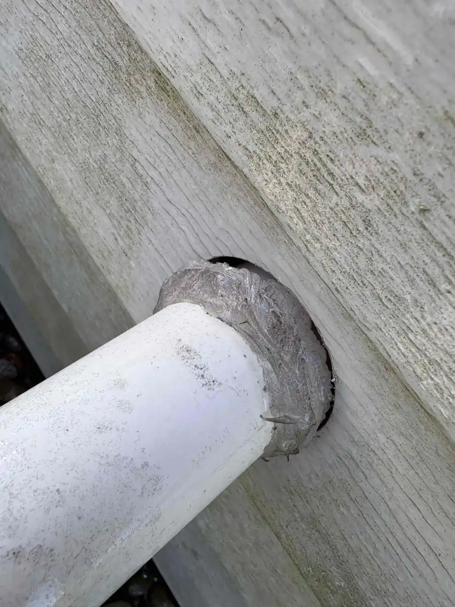 Sump pump discharge pipe exiting a home through the siding above grade