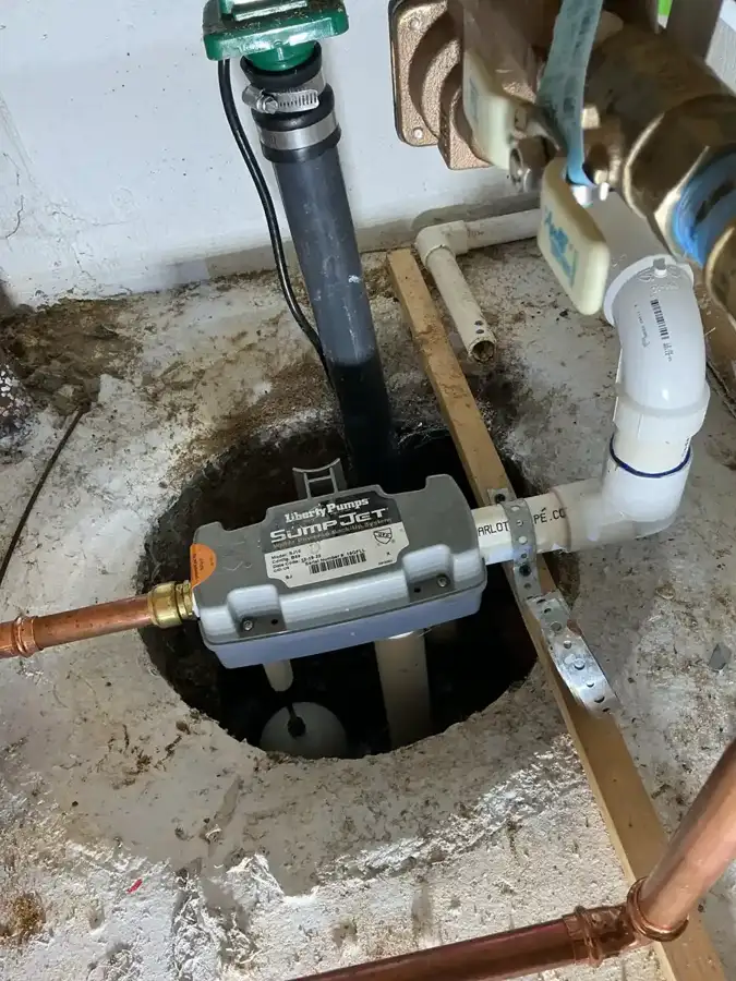 Water powered backup sump pump connected to copper water line above a basement sump pit