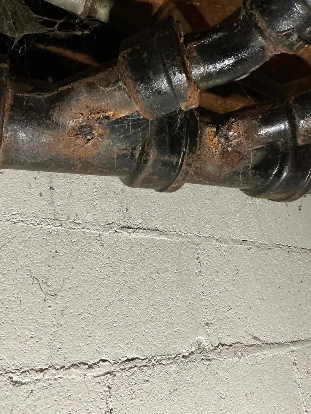 Badly rusted cast iron drain fittings joining at a basement wall
