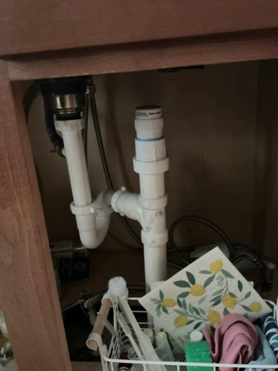 White air admittance vent valve standing above a sink trap under a vanity