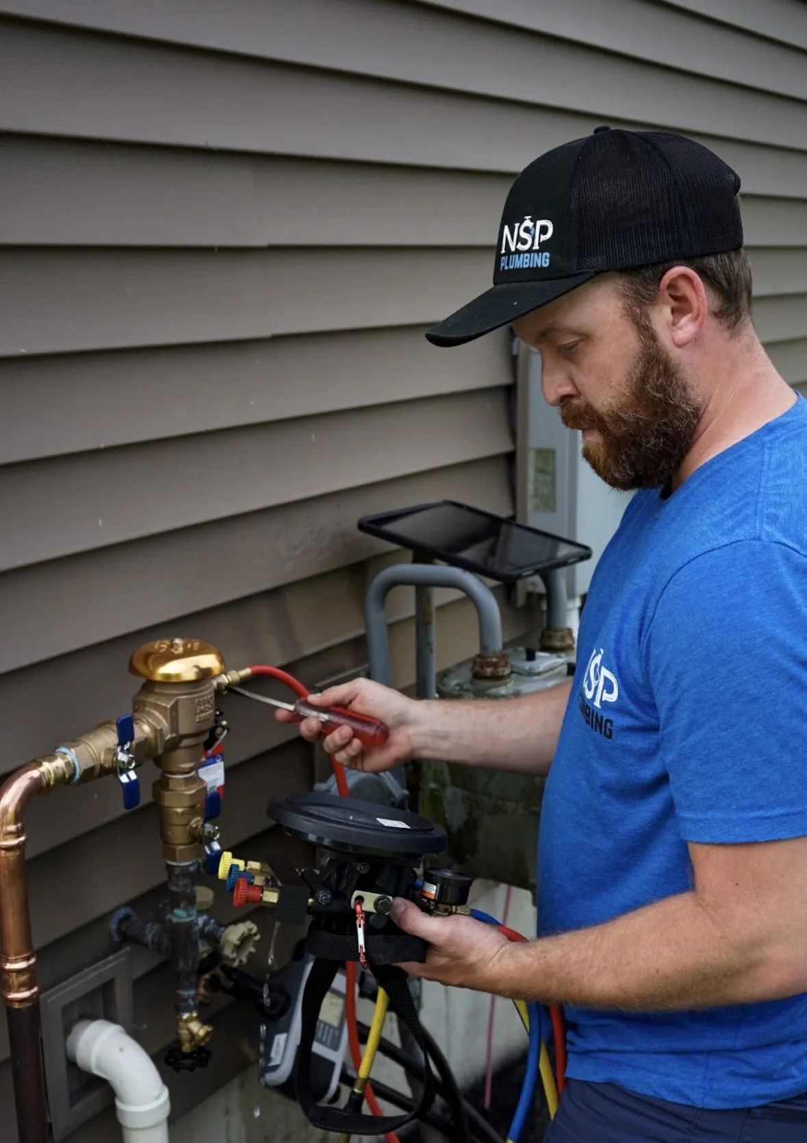NSP Plumbing technician performing a residential backflow test on a sprinkler system in Grand Rapids, MI