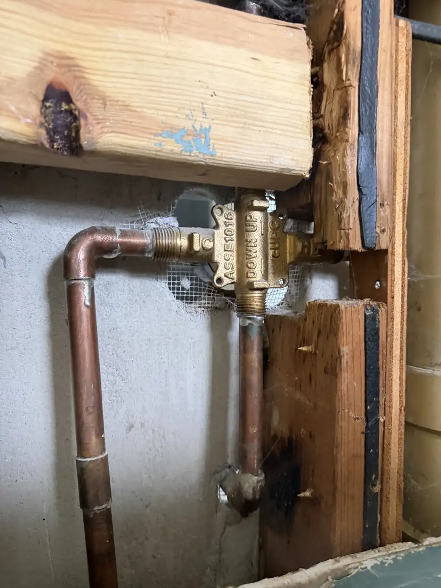 Copper supply lines feeding a brass shower valve inside an opened wall