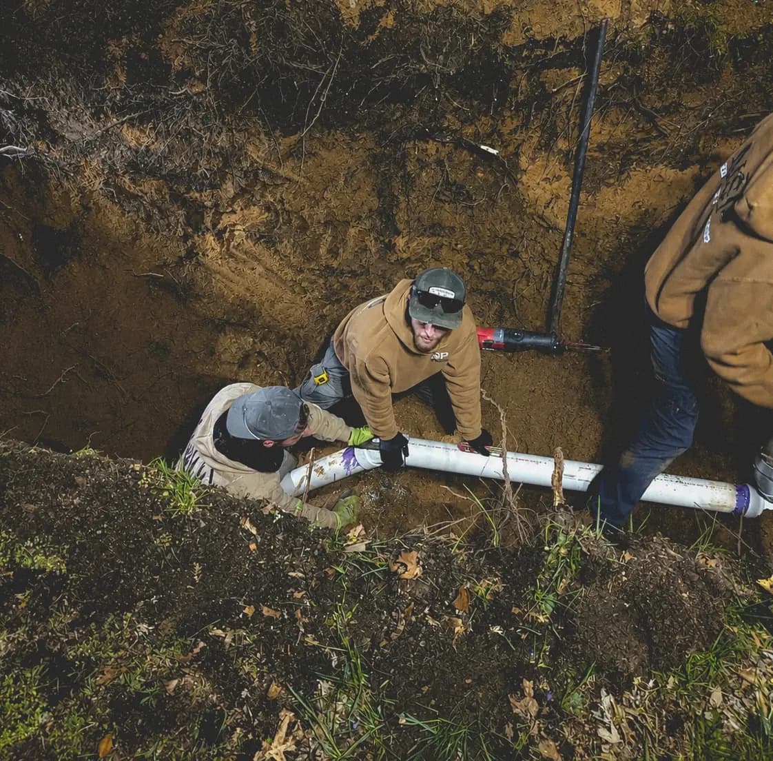 NSP Plumbing crew laying new PVC sewer pipe in an open trench during a sewer line replacement