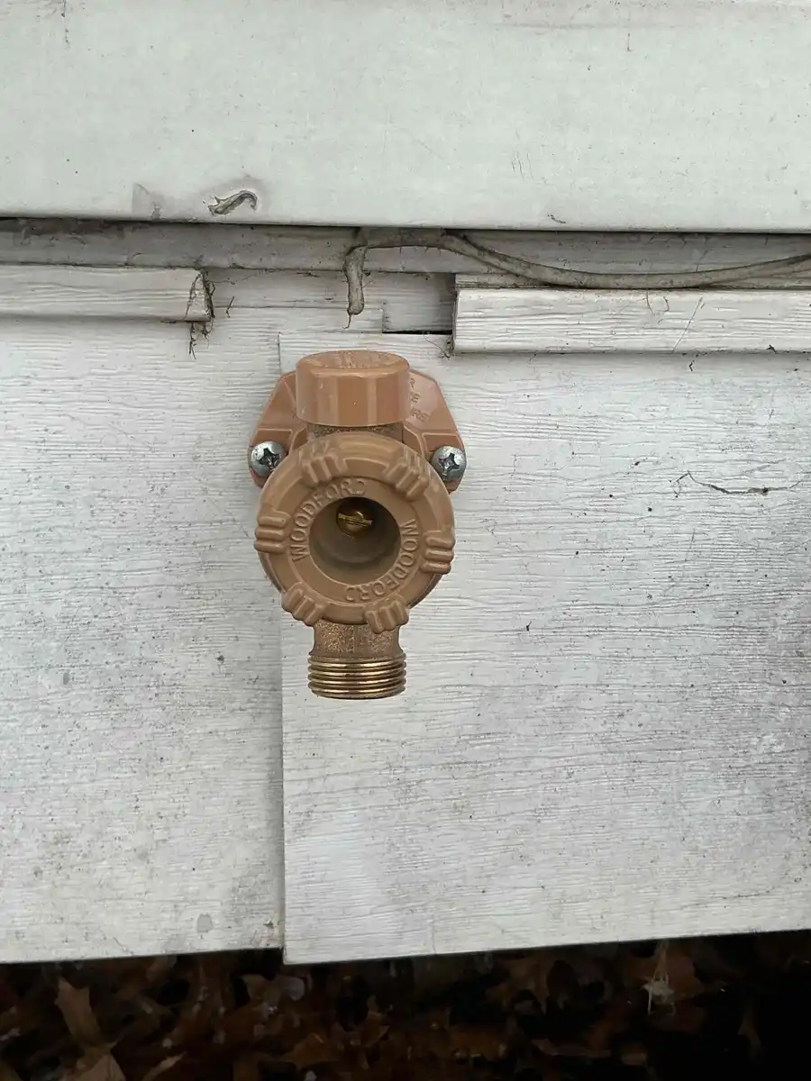 Frost free outdoor faucet with a tan mounting flange installed on siding
