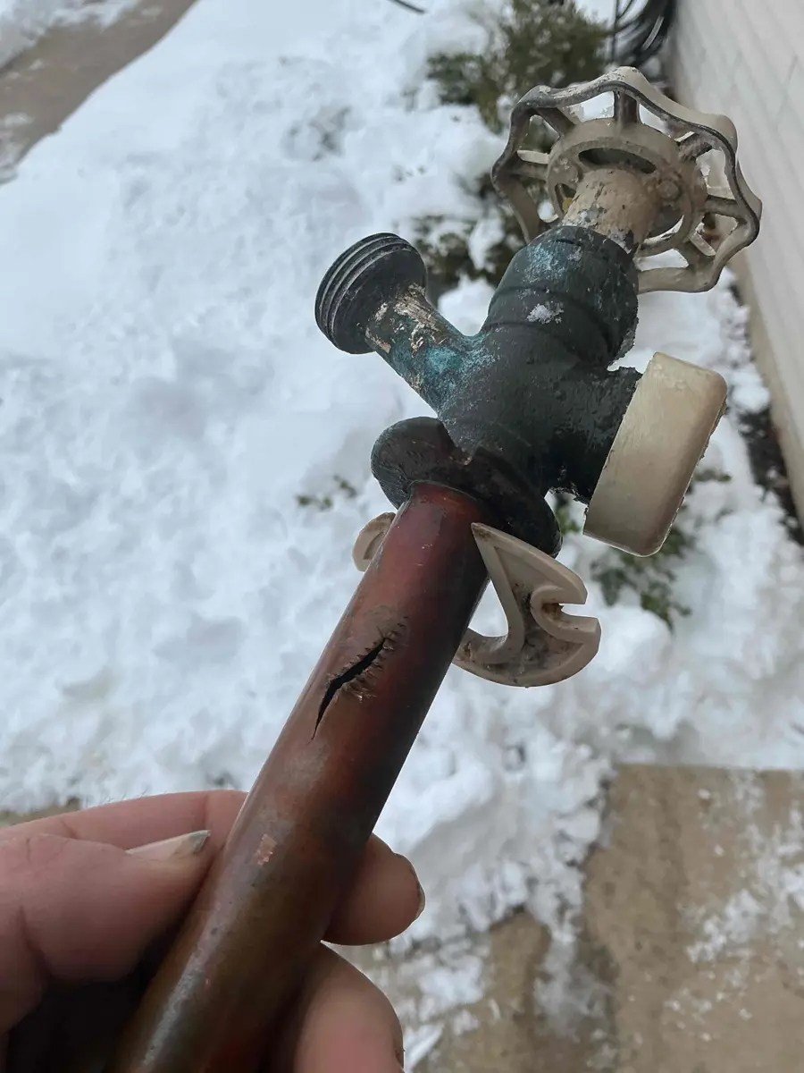 Copper pipe split lengthwise behind a frost free outdoor faucet after freezing