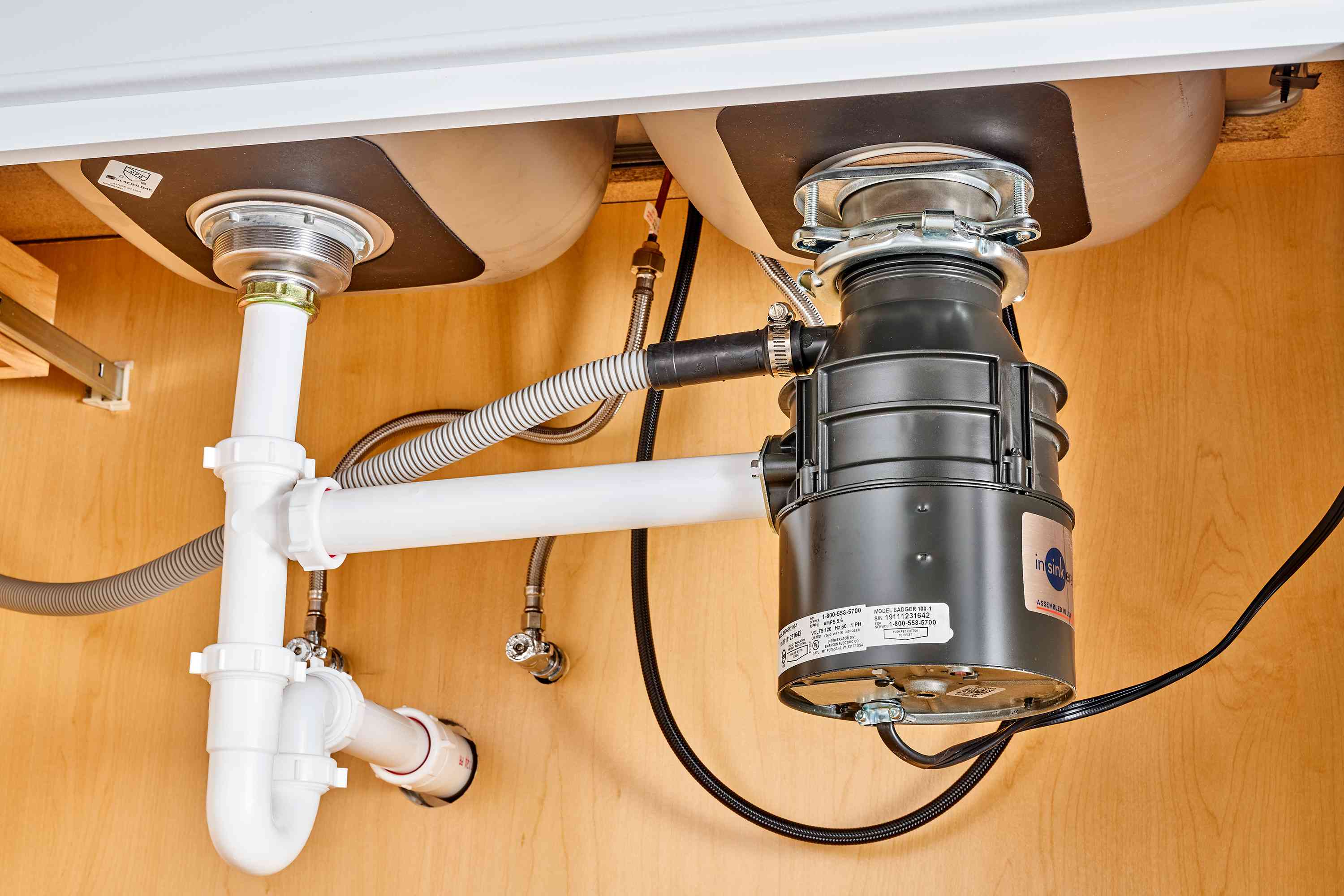 NSP Plumbing licensed plumber installing a garbage disposal under a kitchen sink in Grand Rapids, MI