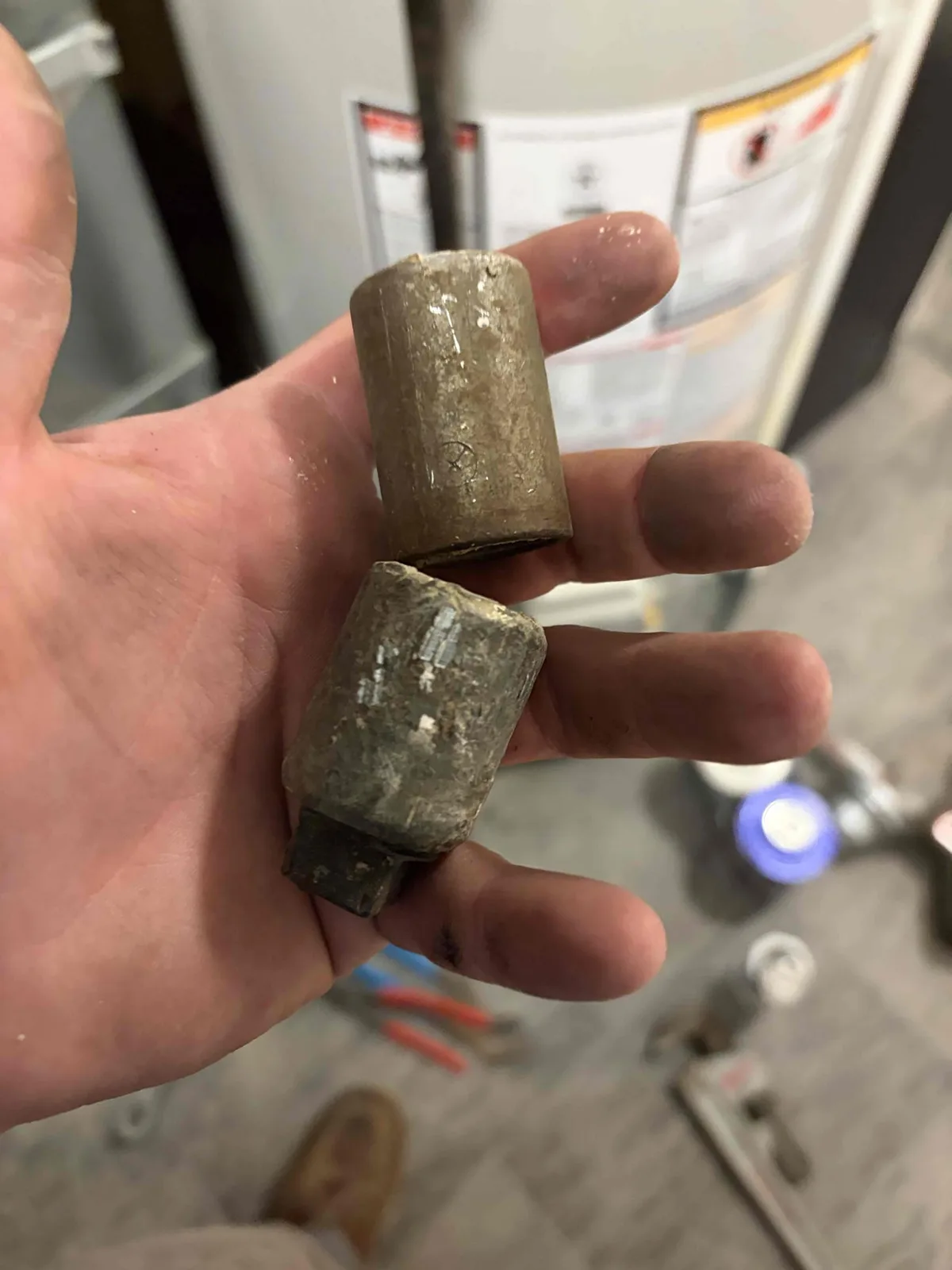 Two heavily scaled pipe nipples cut off a Grand Rapids water heater, coated in white mineral buildup