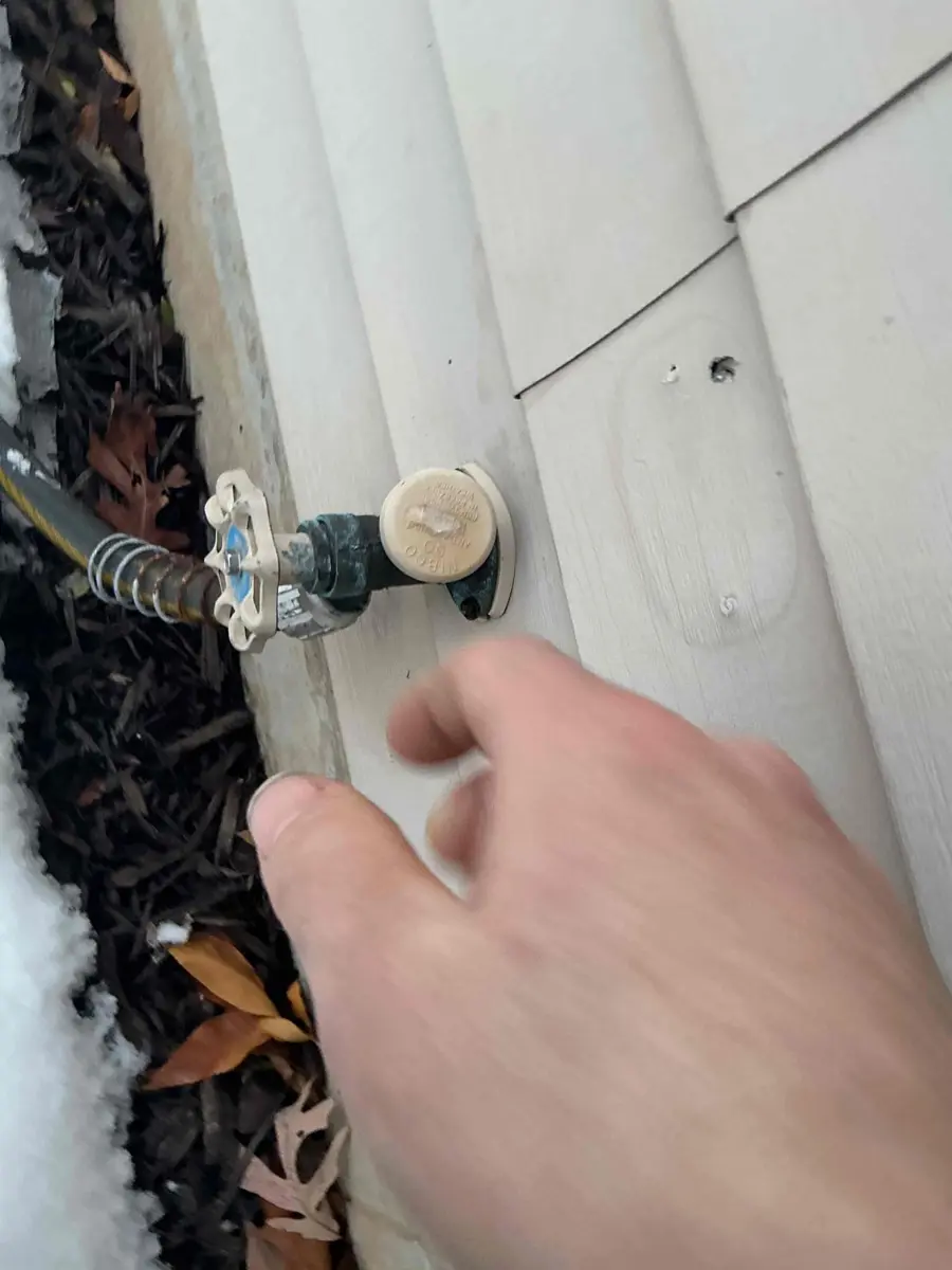 Garden hose still attached to a frost free outdoor faucet in the snow