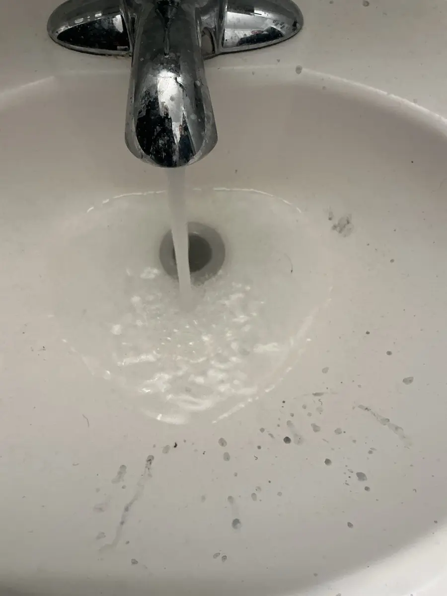 Hot tap water running strongly down a clean bathroom sink drain