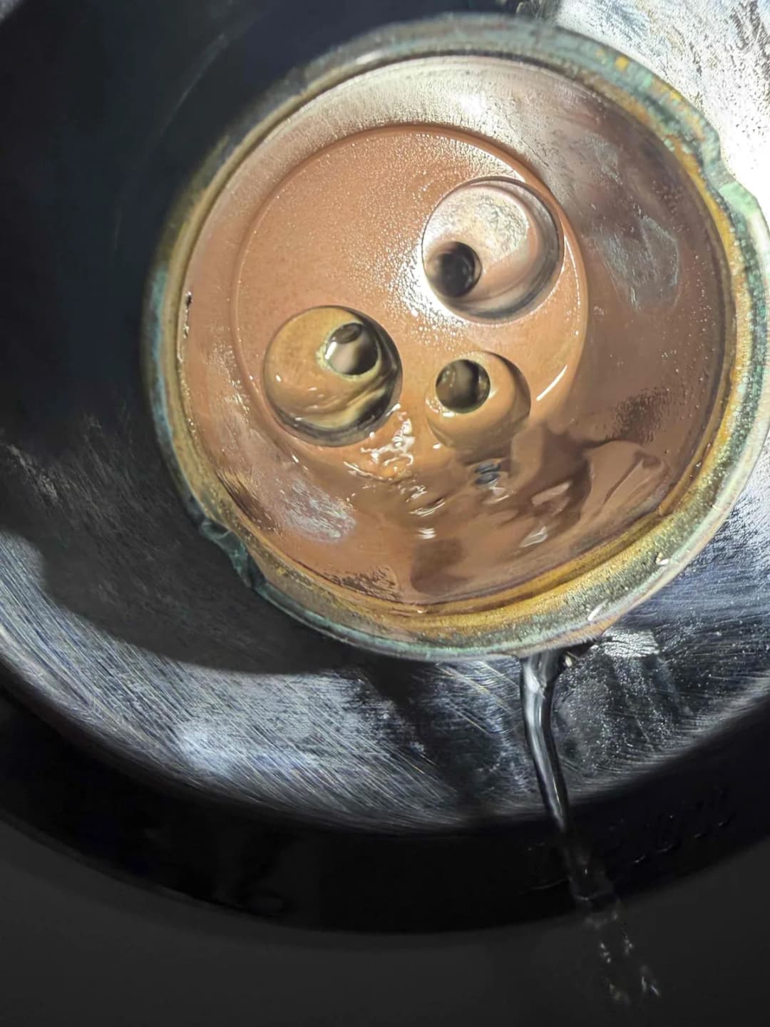 Inside of a brass shower valve body with the cartridge removed showing the water ports and mineral buildup