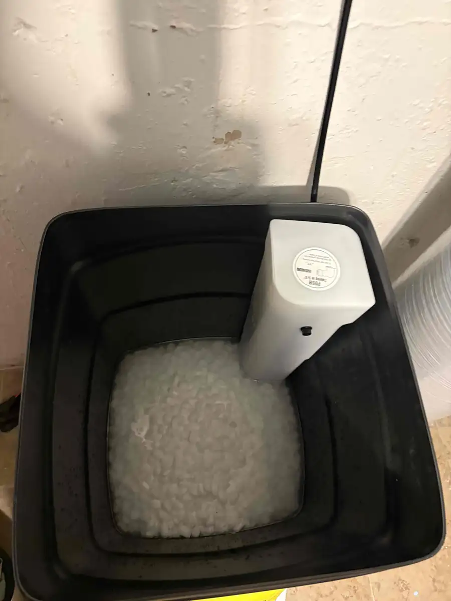 Inside view of a water softener brine tank showing salt pellet level above the water line