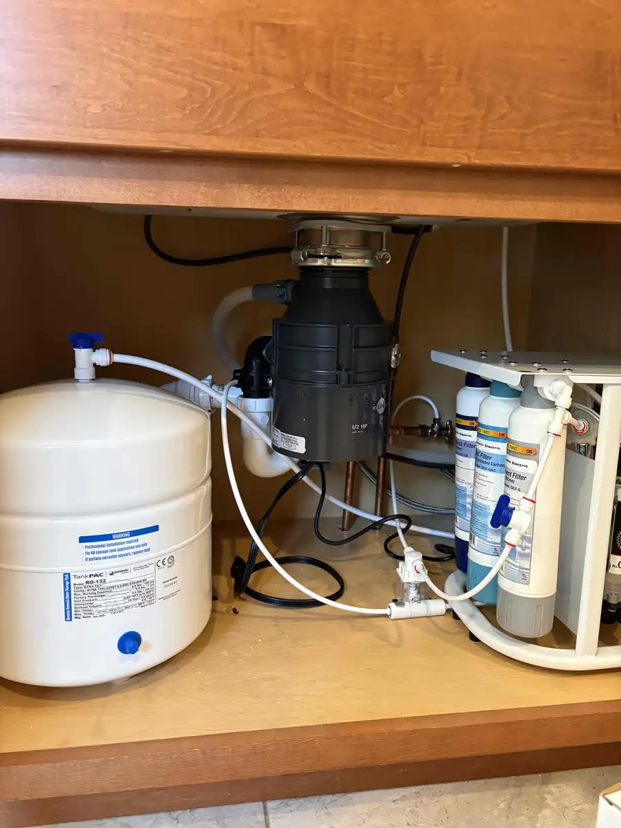 Under-sink reverse osmosis system installed in a West Michigan home showing the pressurized storage tank and multi-stage filter bank