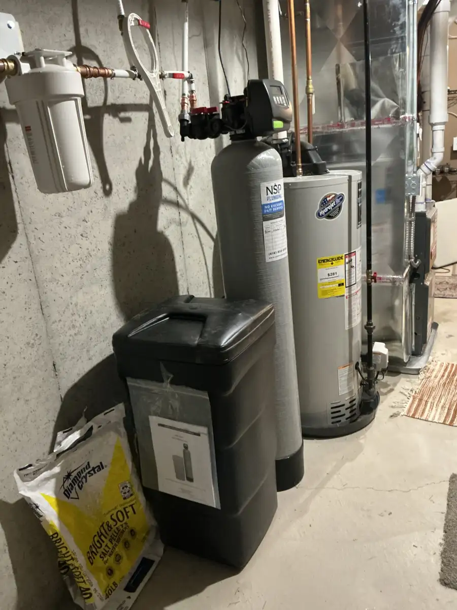 Complete basement water treatment installation with whole-home sediment filter, water softener, brine tank, and water heater