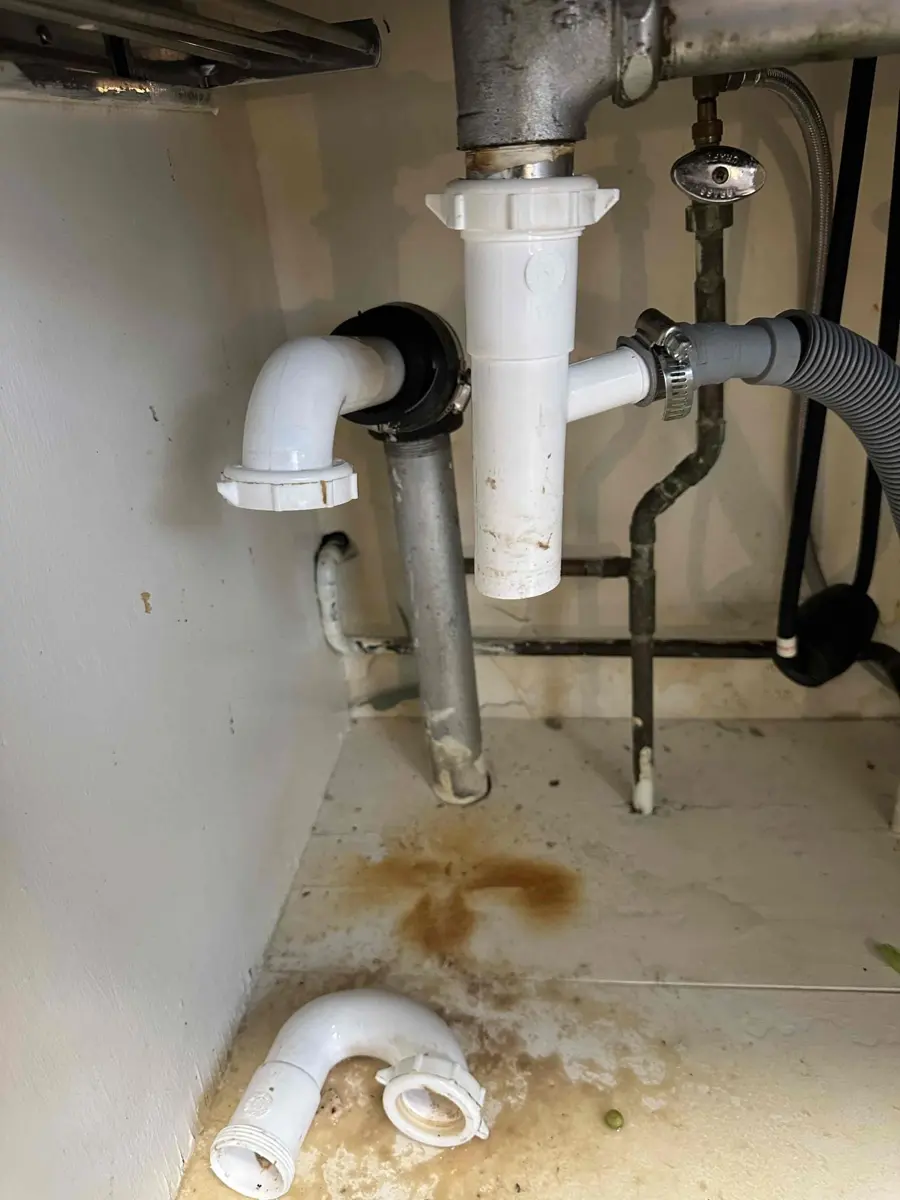 Kitchen sink trap disconnected with the curved pipe lying in the cabinet