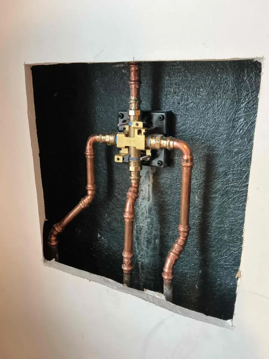 New shower valve with copper hot and cold lines and the shower riser installed in an open wall