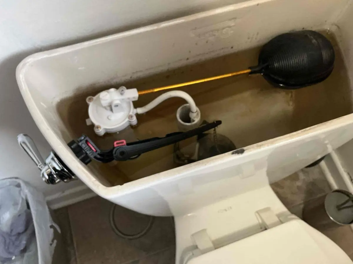 Old style float ball fill valve on a long brass arm inside a constantly running toilet tank