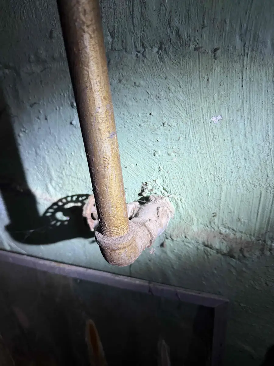 Old corroded galvanized water supply pipe entering a basement wall, a common low pressure cause
