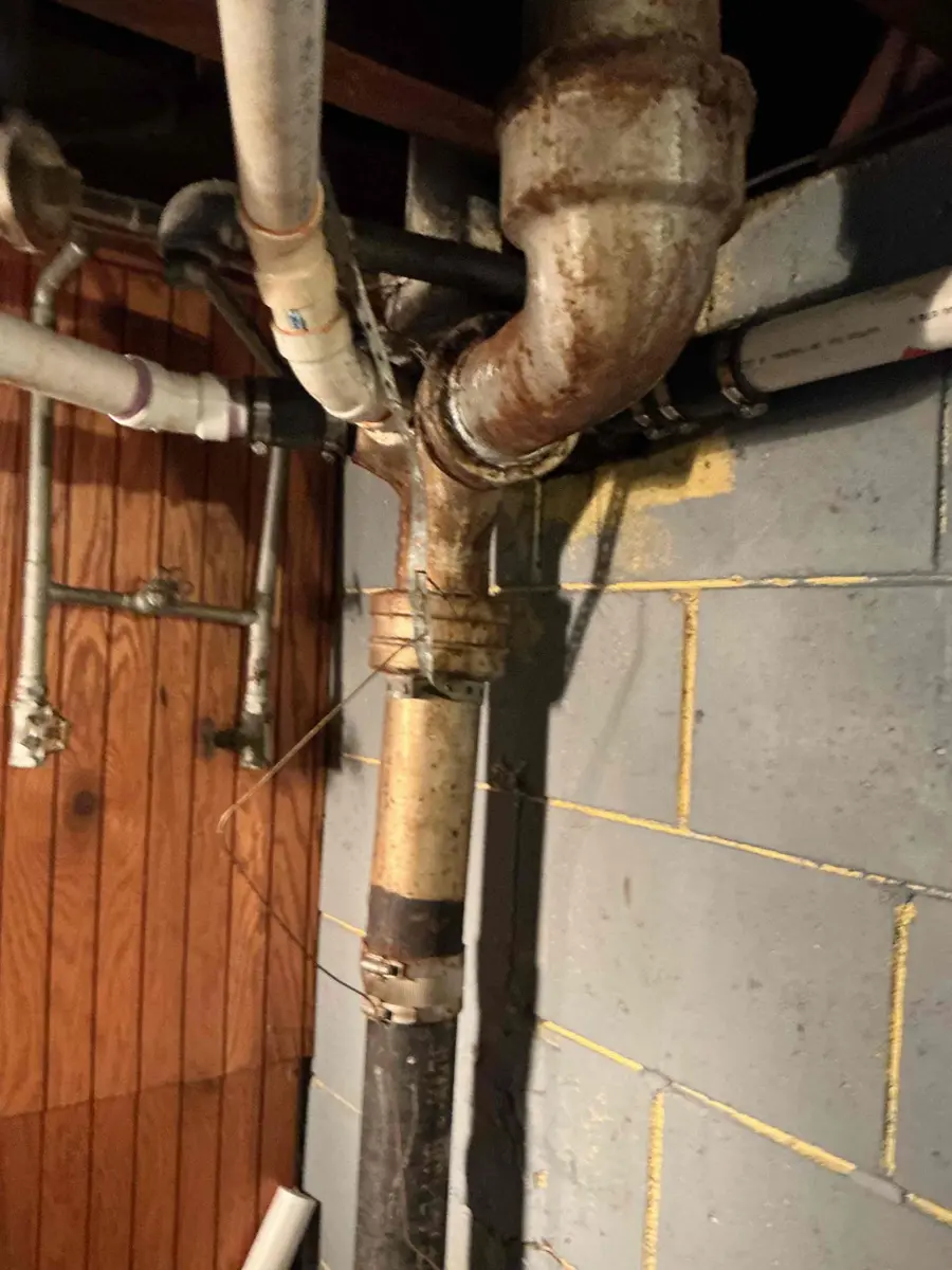 Old metal kitchen drain line and fittings running through an unfinished basement