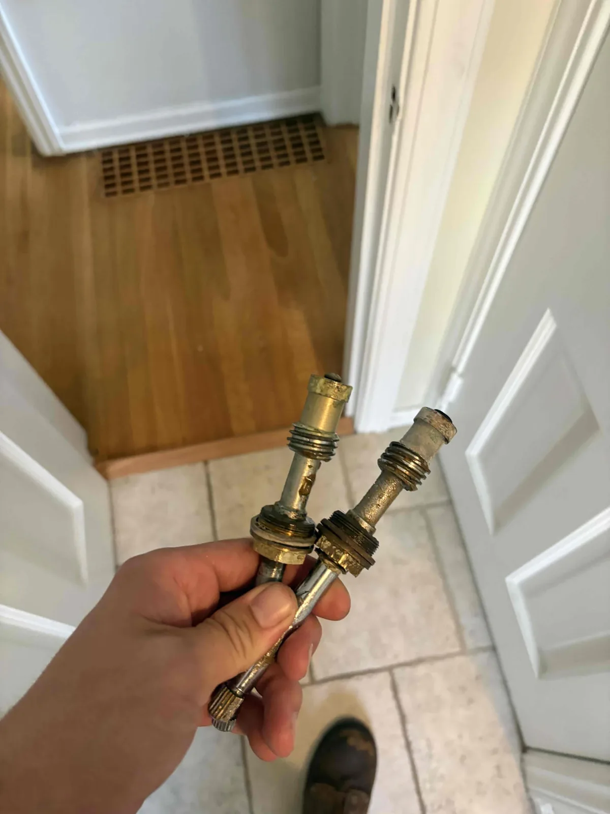 Two old brass shower stems pulled from a three handle shower valve