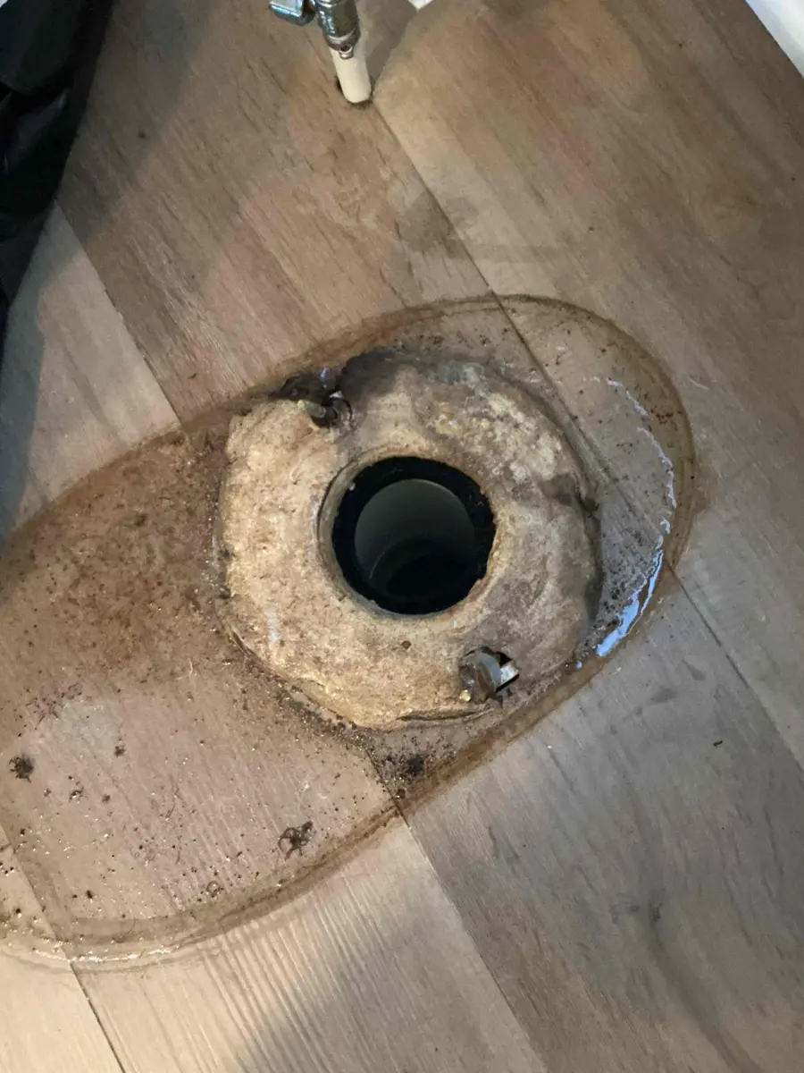 Old crushed wax ring sitting on a toilet flange after the toilet was removed for a leak at the base