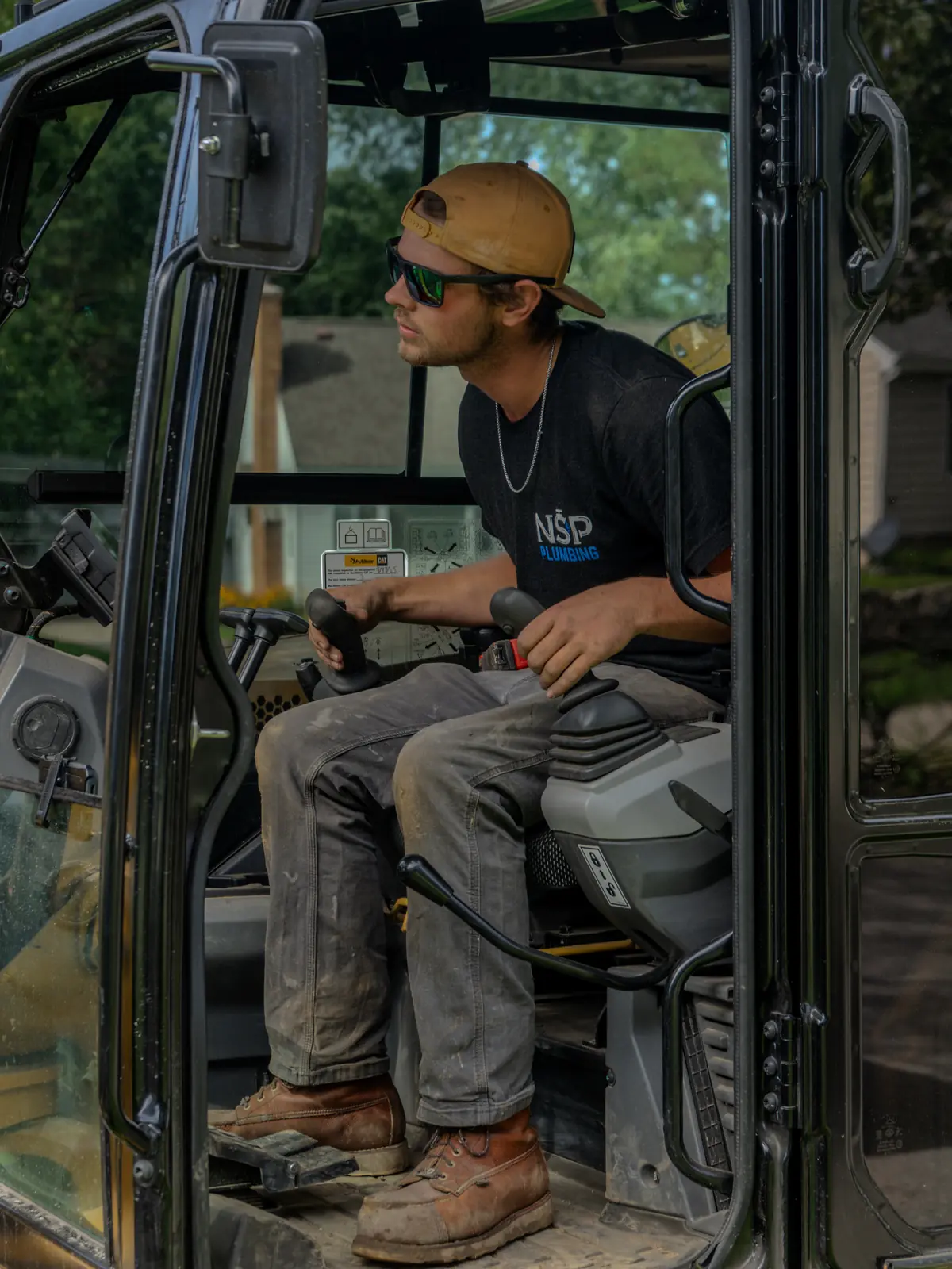 NSP Plumbing plumber operating a mini excavator on a residential sewer line replacement