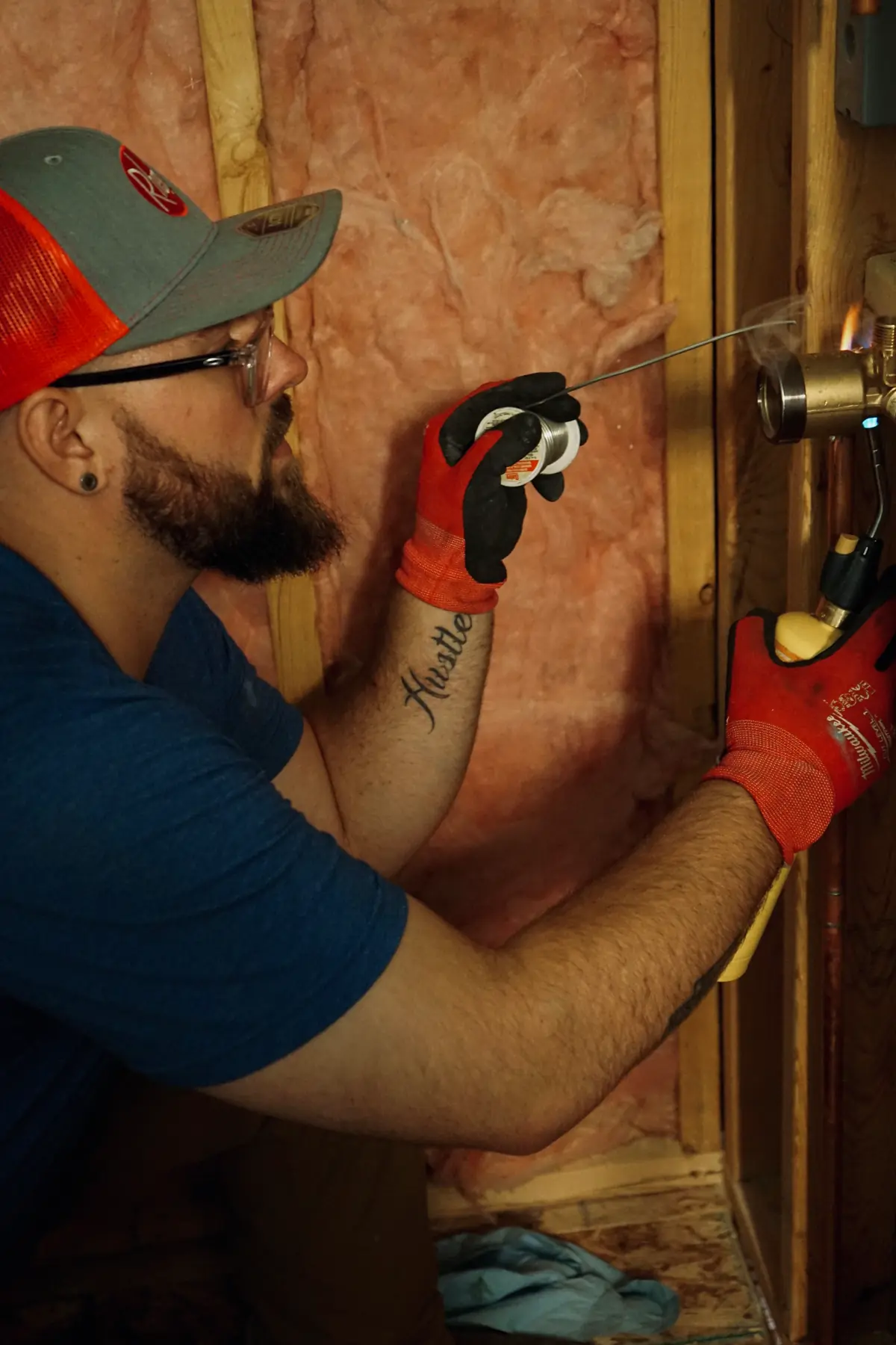NSP Plumbing plumber soldering a new shower valve inside an open bathroom wall