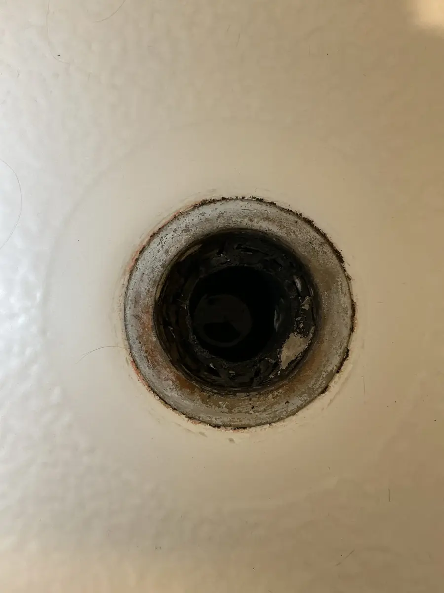 Shower drain body with the strainer removed showing rust and buildup around the inside of the opening