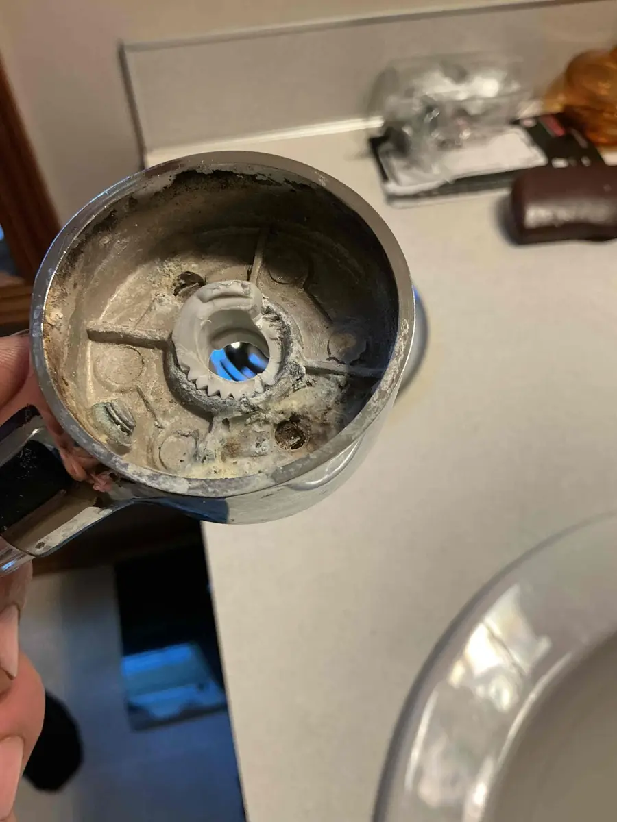 Shower handle removed from the wall showing white mineral scale built up inside the hub