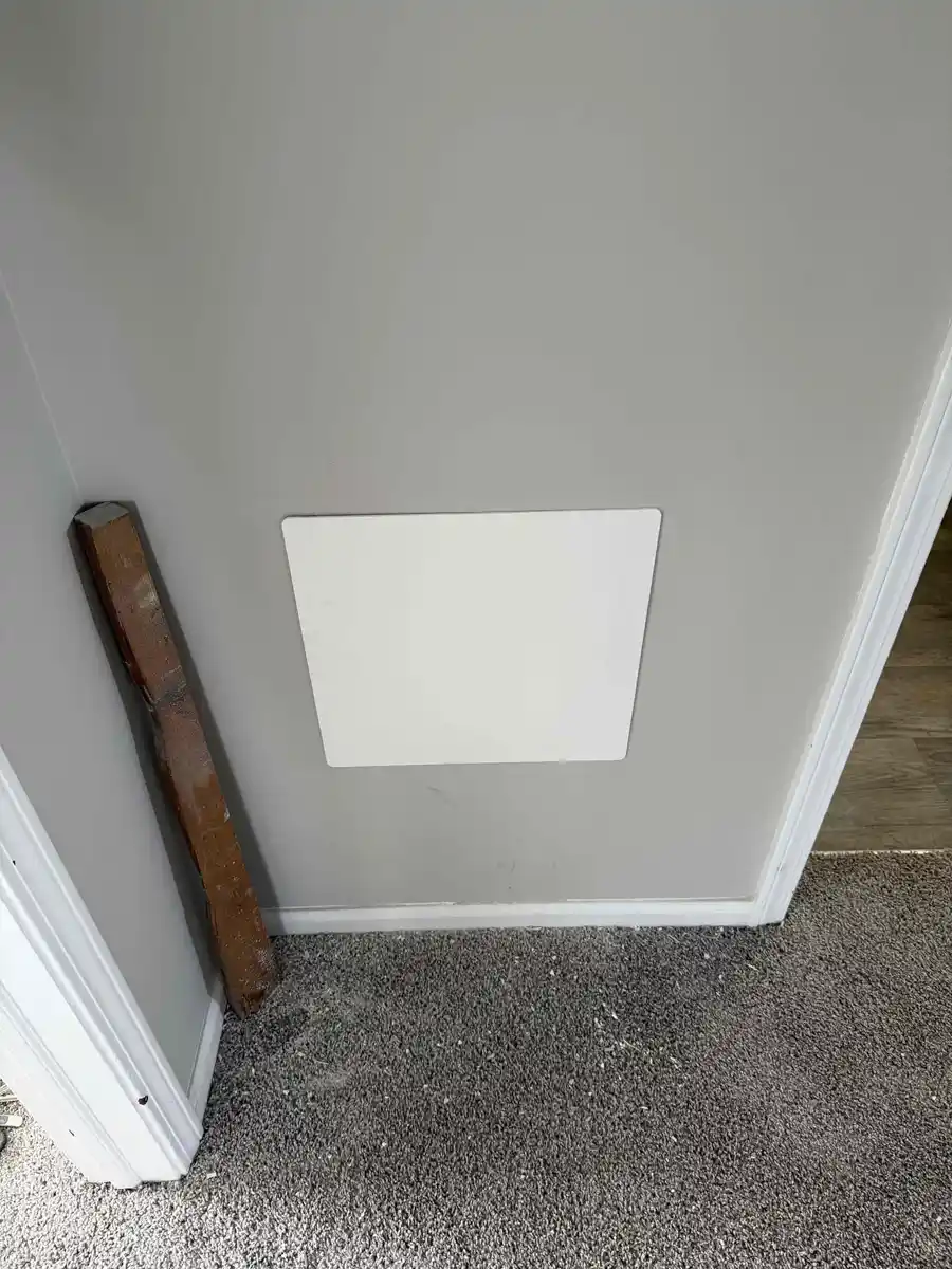Small white access panel on a bedroom wall behind the shower valve