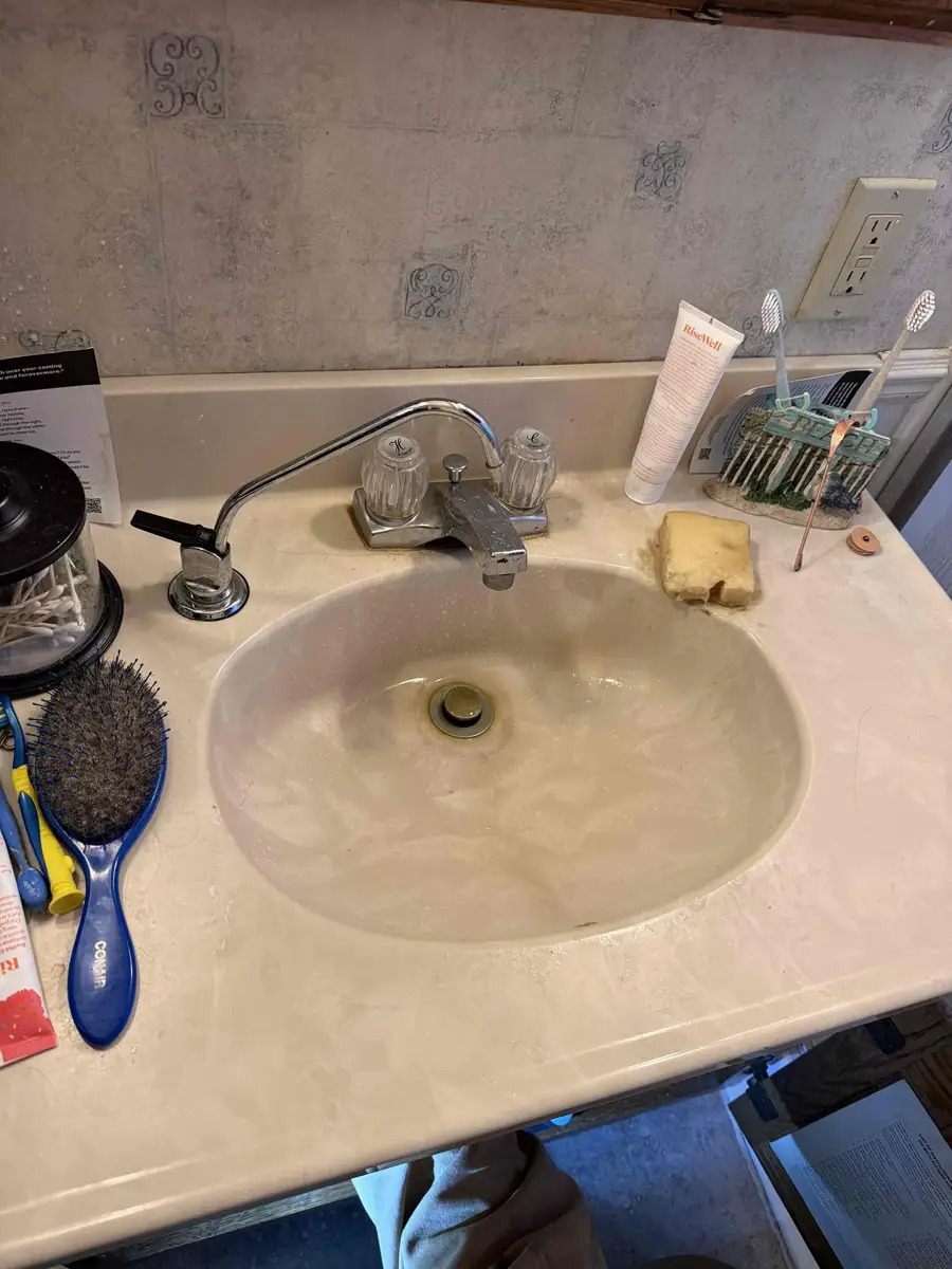 Bathroom sink with a stained basin and a drain that smells when water runs