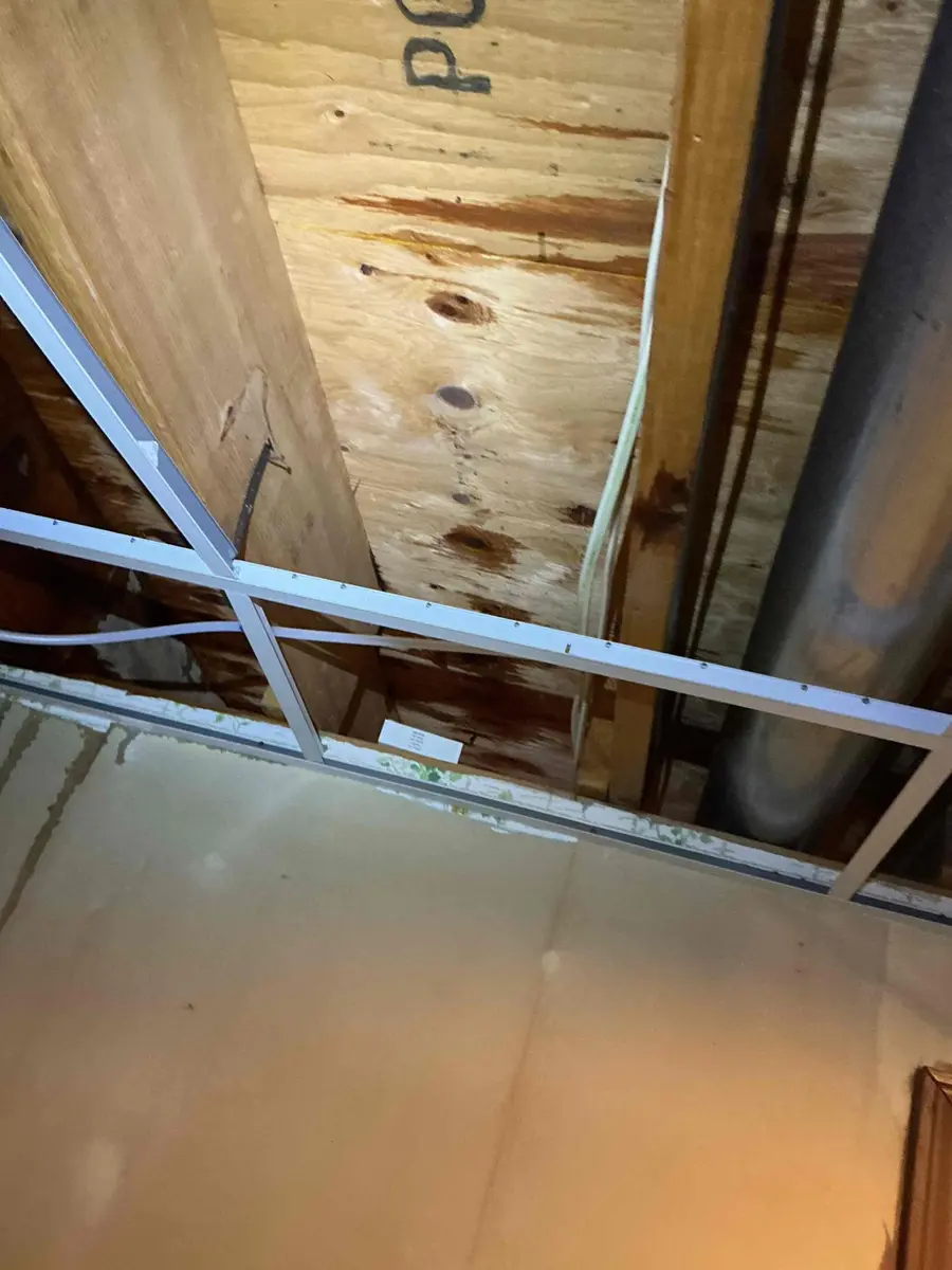 Water stained wooden floor joists and subfloor in an opened basement ceiling after a leak